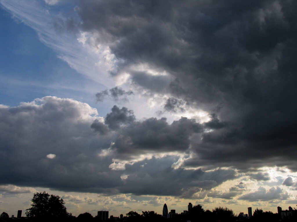 City of London skyline seen from Hackney on Saturday 20 December 2003 at 15:37, with The Gherkin, Tower 42, and One Canada Square silhouetted beneath thick stratocumulus and nimbostratus clouds.
