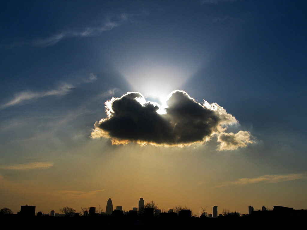 City of London skyline viewed from Hackney with a dramatic sunburst piercing a cumulus congestus cloud above The Gherkin, Tower 42, and One Canada Square on Saturday 27 November 2003.
