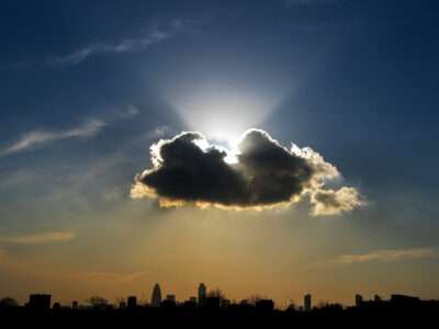 City of London skyline viewed from Hackney with a dramatic sunburst piercing a cumulus congestus cloud above The Gherkin, Tower 42, and One Canada Square on Saturday 27 November 2003.
