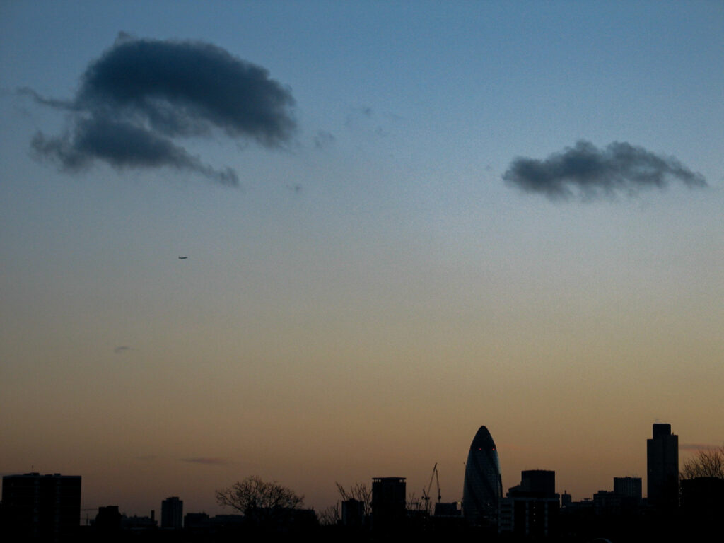 City of London skyline from Hackney with The Gherkin, Tower 42, and One Canada Square at dusk, silhouetted beneath patches of altocumulus and stratocumulus clouds, Monday 12 January 2004.