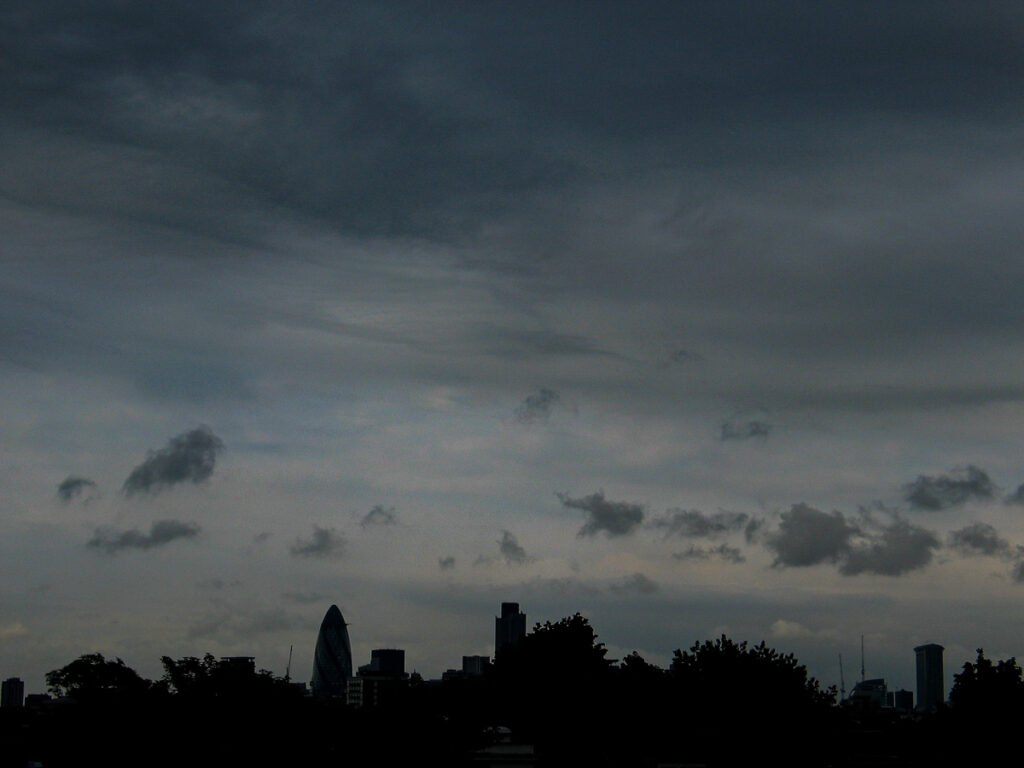 City of London skyline seen from Hackney at sunrise with The Gherkin, Tower 42, and One Canada Square beneath dense stratocumulus and nimbostratus clouds, Friday 21 May 2004.