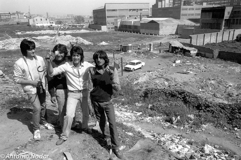 Group of young people standing on a hillside overlooking makeshift shacks and debris in the former Perona shanty town near Barcelona.