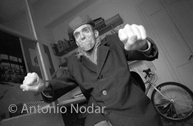 Carlos Moro makes an expressive gesture with both arms extended forward, inside his Barcelona home.