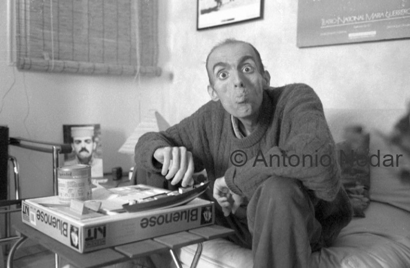 Carlos Moro sits on a couch, leaning forward beside a tray with medicines and canned food, in his Barcelona home.