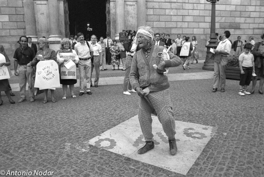 Woman in a dress strikes a dramatic flamenco pose while standing alone on a narrow Barcelona street, 1990s.