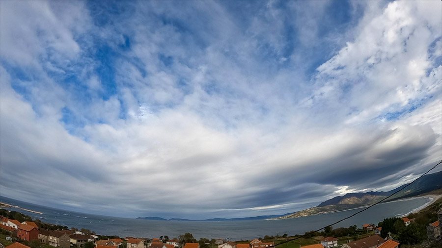 Early‑afternoon panoramic view over Carnota Bay on the Costa da Morte with mixed altocumulus and stratocumulus clouds and blue gaps above Sofán village, Monte Pindo, Caldebarcos and Cape Fisterra.