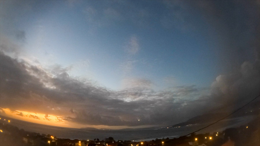 Dusk view over Carnota Bay on the Costa da Morte with layered altostratus and stratocumulus clouds, orange sunset band and village lights around Monte Pindo, Caldebarcos and Cape Fisterra.