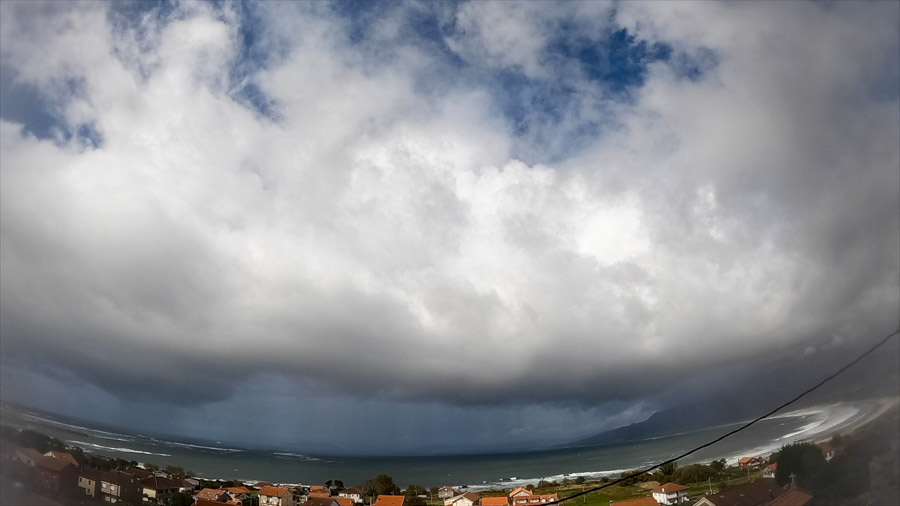 Panoramic view of stormy stratocumulus and nimbostratus clouds over Carnota Bay on the Costa da Morte, seen above the rooftops of Sofán village with Monte Pindo, Caldebarcos and Cape Fisterra in the distance.