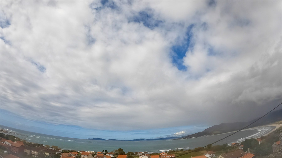 Panoramic daylight scene over Carnota Bay on the Costa da Morte with a developing cumulonimbus cloud line under a blue sky above the rooftops of Sofán, Monte Pindo, Caldebarcos and Cape Fisterra.